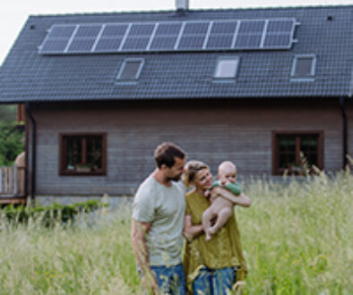 Happy family with baby near their house with solar panels. Alternative energy, saving resources and sustainable lifestyle concept.